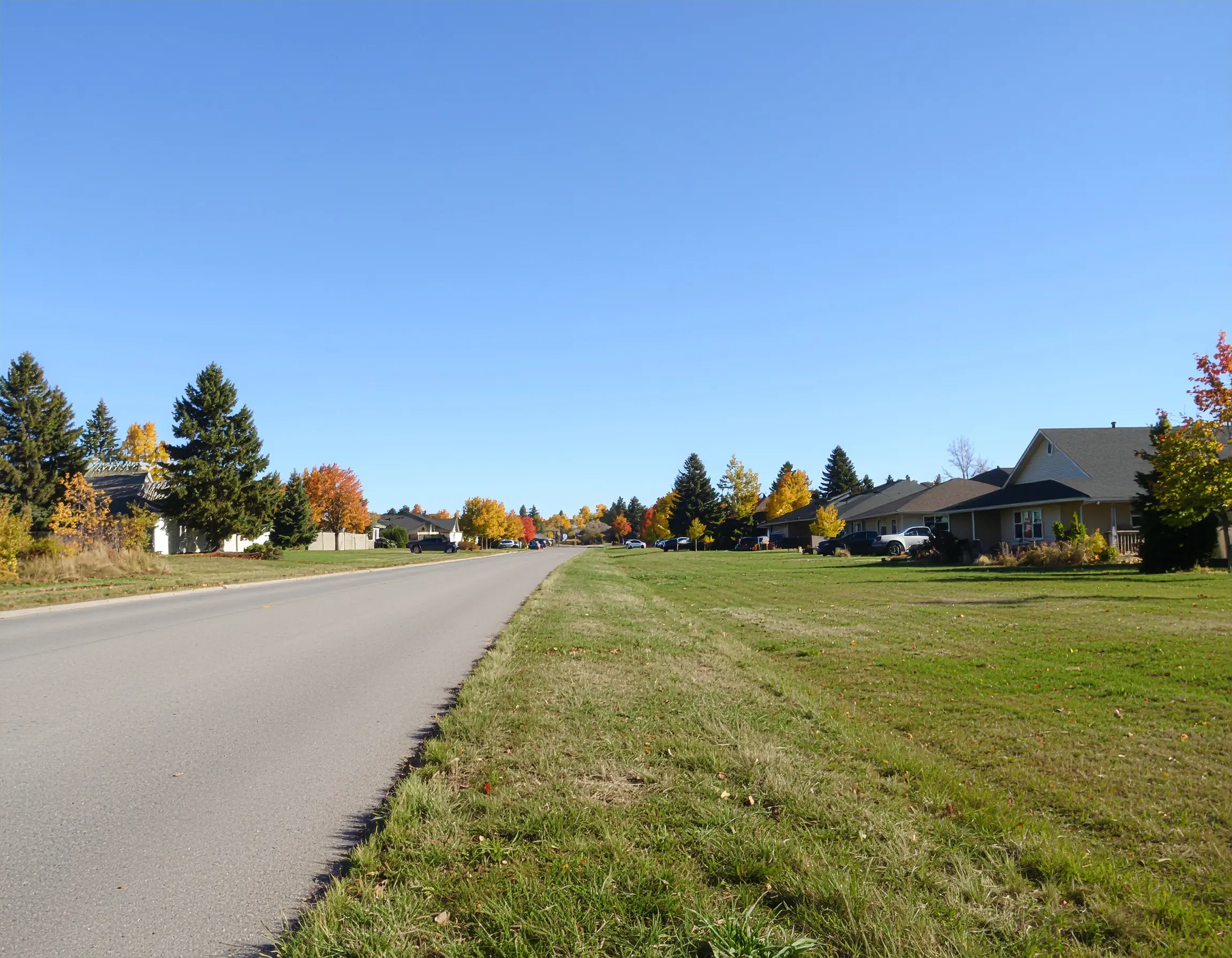 A bright autumn day in Swift Current, Saskatchewan, showing suburban homes with yellow and orange tree-lined streets under clear skies.